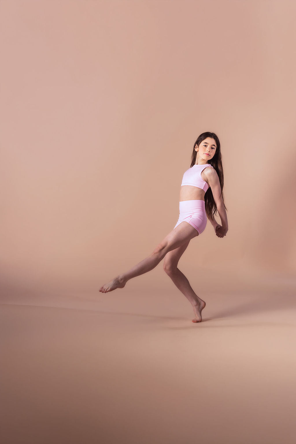 Dancer in a white outfit posing on a beige background