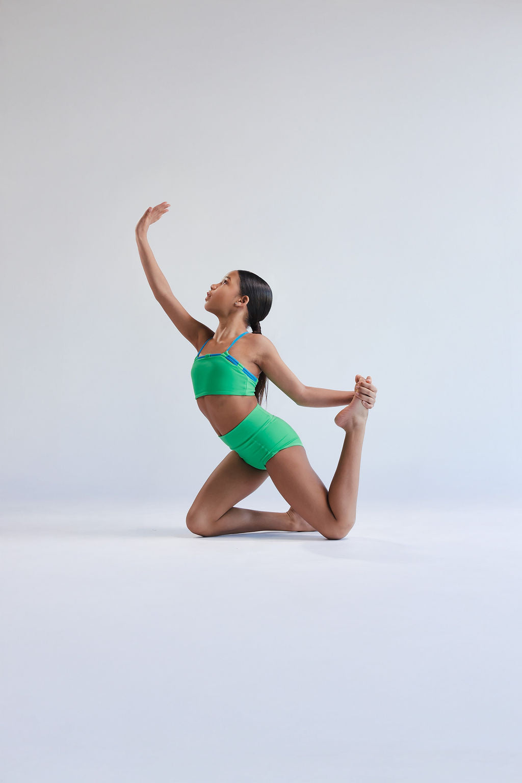 Person in a green dancewear posing on a white background