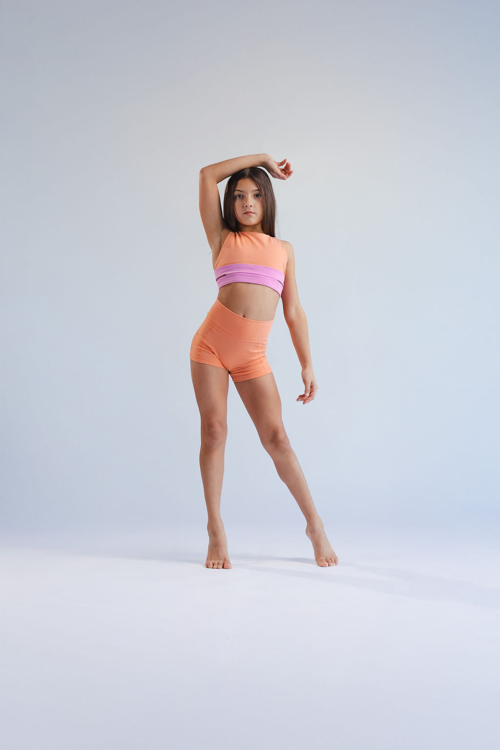 Person wearing an orange and pink two-piece outfit on a light gray background