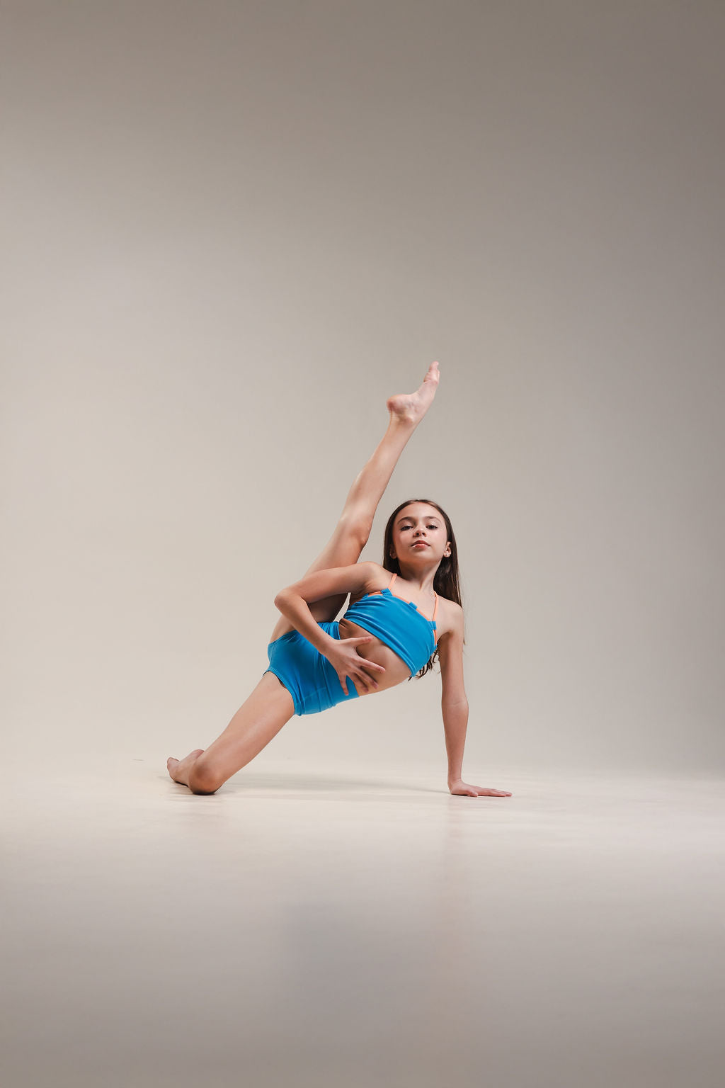 Dancer in a blue outfit performing a pose on a plain background